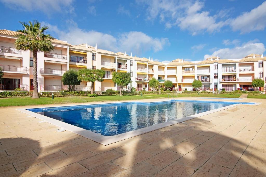 a swimming pool in front of a large apartment building at Columbus Beach Apartment in Quarteira
