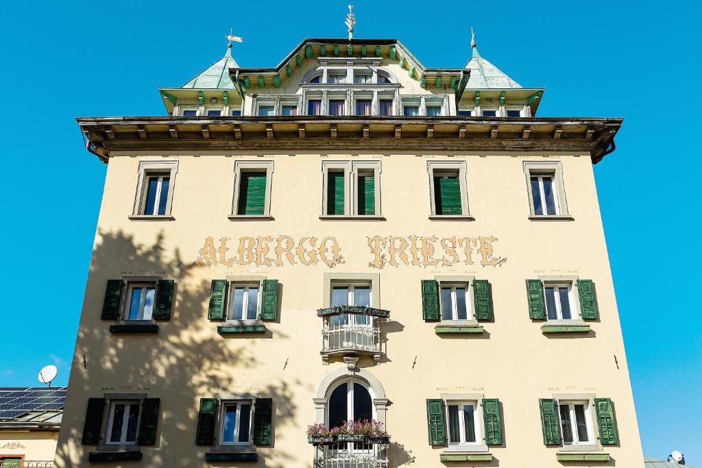 un edificio alto con un cartello sopra di Albergo Trieste - Lorenzago a Lorenzago