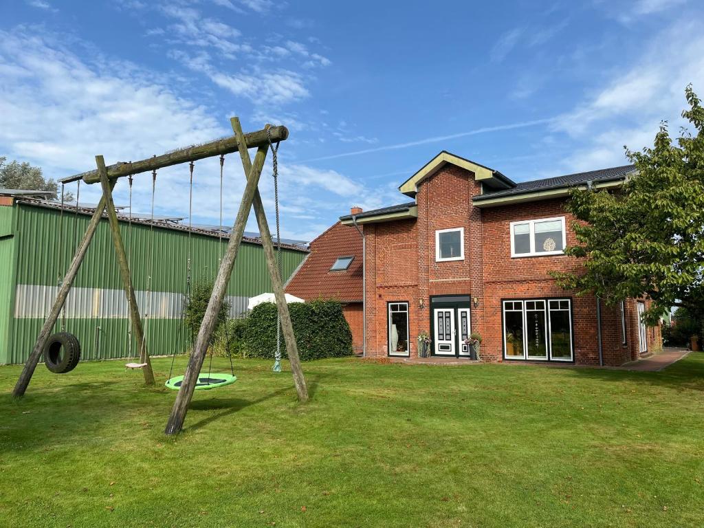 a swing set in a yard in front of a house at Ferienhof Anke Thiede in Lehe