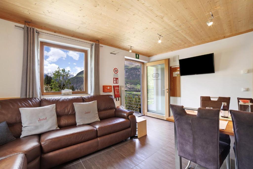 a living room with a brown leather couch and a table at Joshof Bergblick in Moso