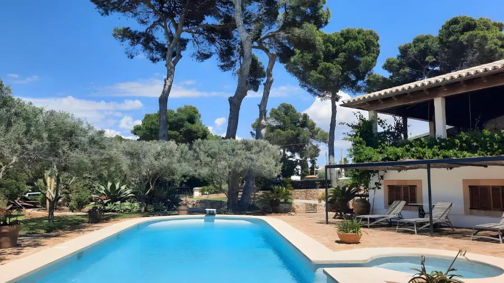 a swimming pool in front of a house with trees at Charming villa by the sea in Llucmajor