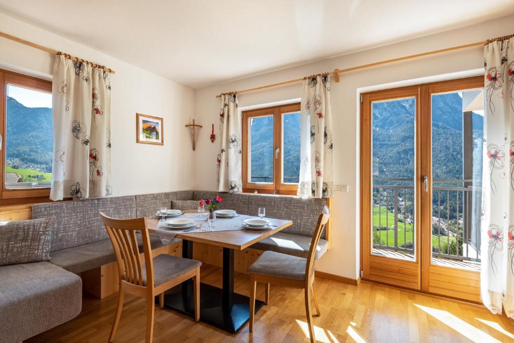 a dining room with a table and chairs and windows at Thusnelda Apartment C in Siusi