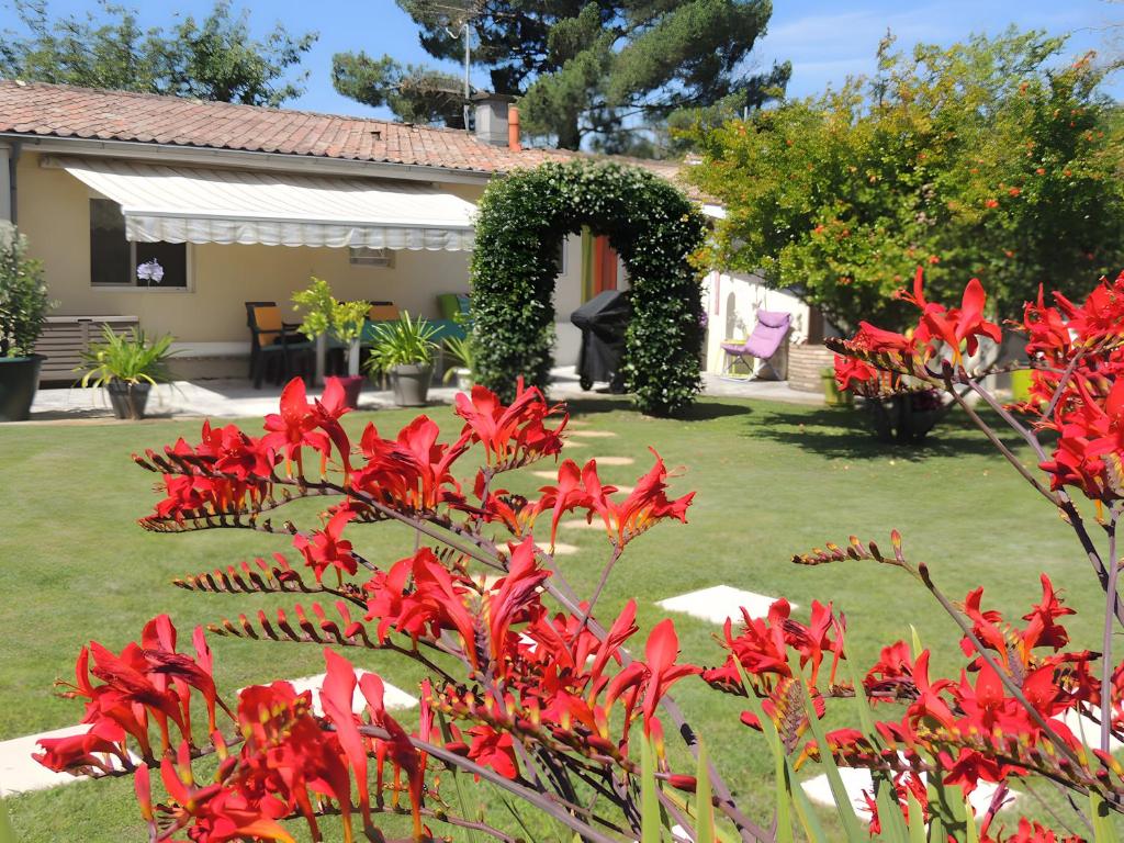 a garden with red flowers and an arch at Sweet Home - Gujan-Mestras in Gujan-Mestras