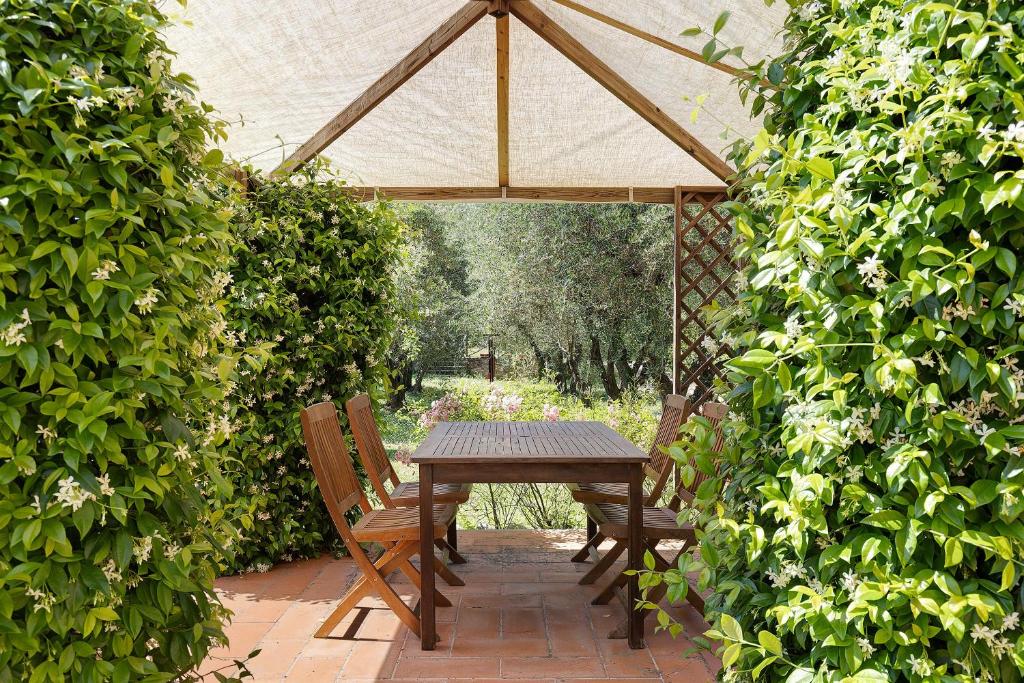 a wooden table and two chairs under an umbrella at La Ripa - Appartamento Il Fienile in San Gimignano
