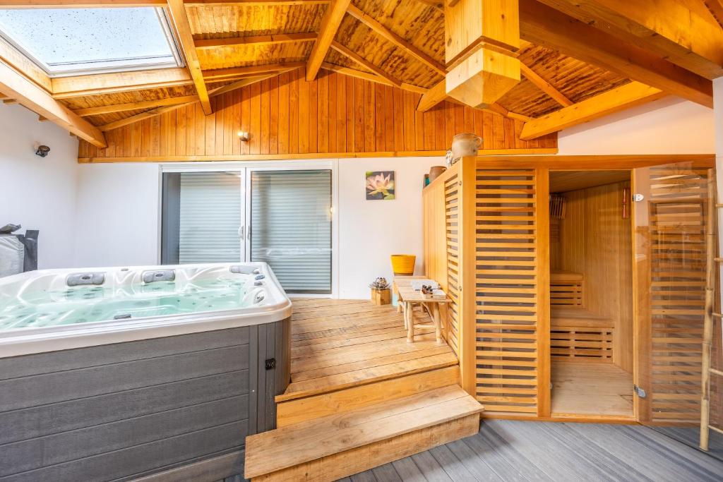 a hot tub in a room with a wooden ceiling at Chambres D'hôtes Le Palmier in Sevremont