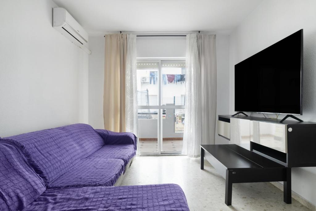 a living room with a purple couch and a tv at Casa En El Centro De Barbate in Barbate