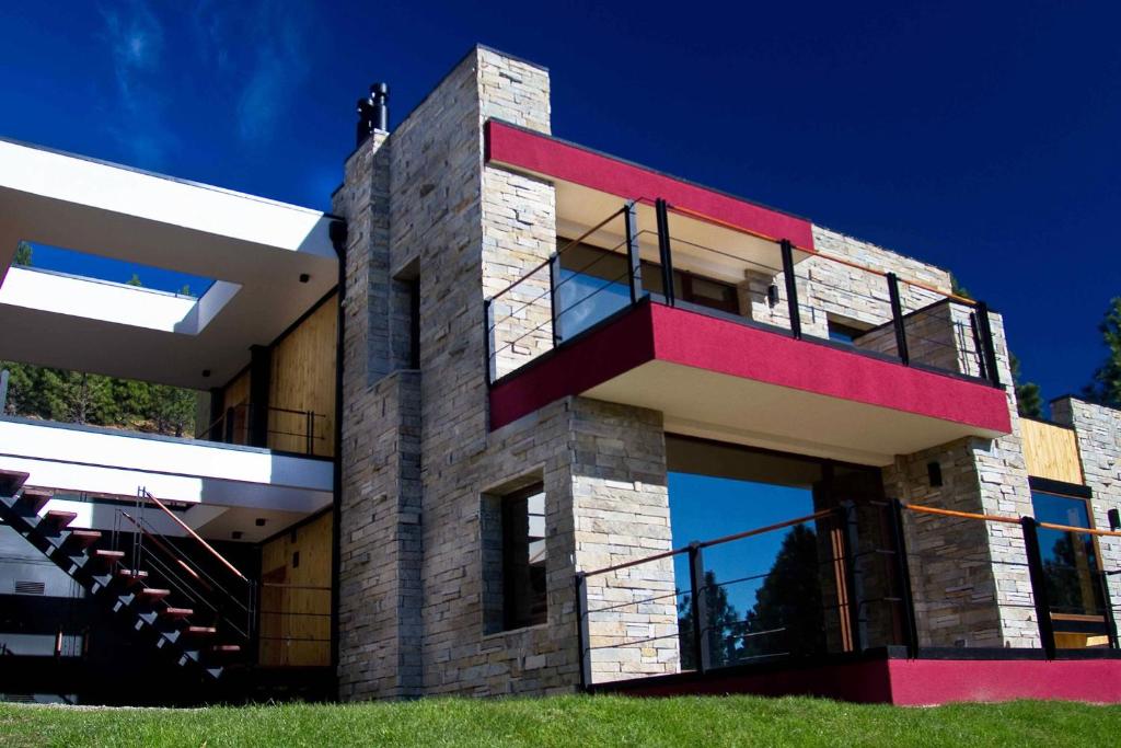 a house with a red balcony on the side of it at Casa de Montaña Golf & Polo - San Martin de los Andes in San Martín de los Andes