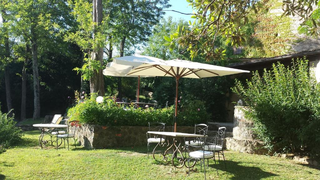 a table and chairs with an umbrella in a yard at B&B Countryhouse Villa Baciolo in San Gimignano
