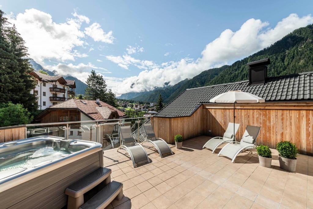 a patio with chairs and a hot tub on a roof at Apartment Cinch Residence Bun Ste in San Vigilio Di Marebbe