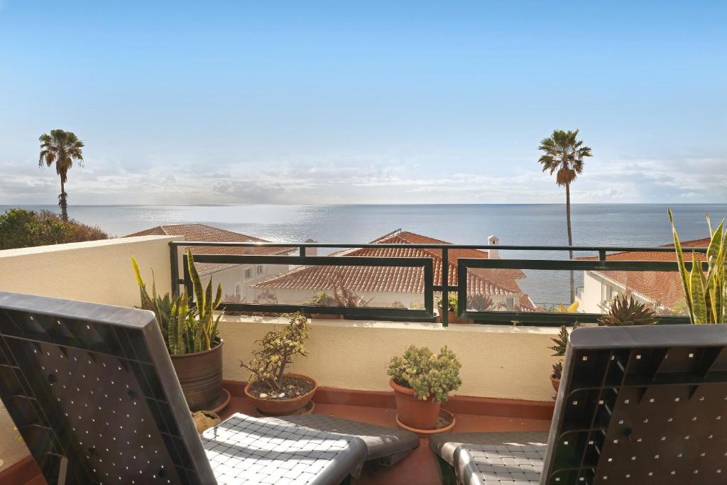 a balcony with chairs and potted plants and the ocean at Luzias Apartment in Funchal