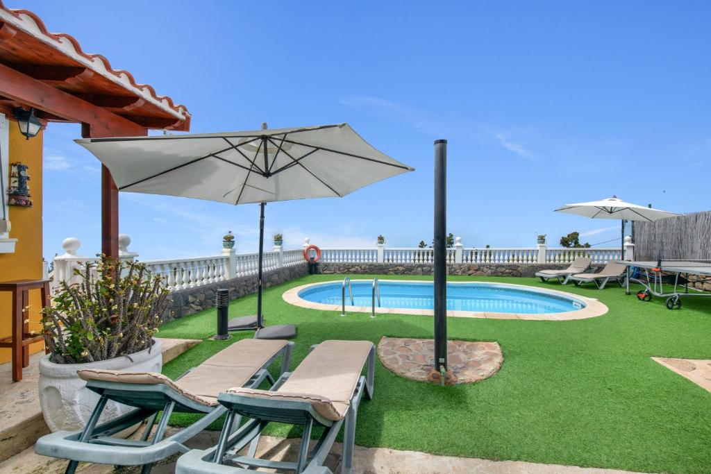 a patio with chairs and an umbrella and a pool at Vv Terrazita in Tijarafe