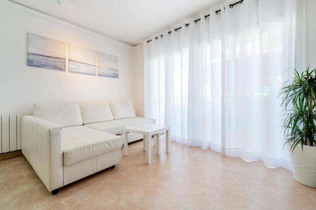 a living room with a white couch and a table at Center Beach Calafell in Calafell