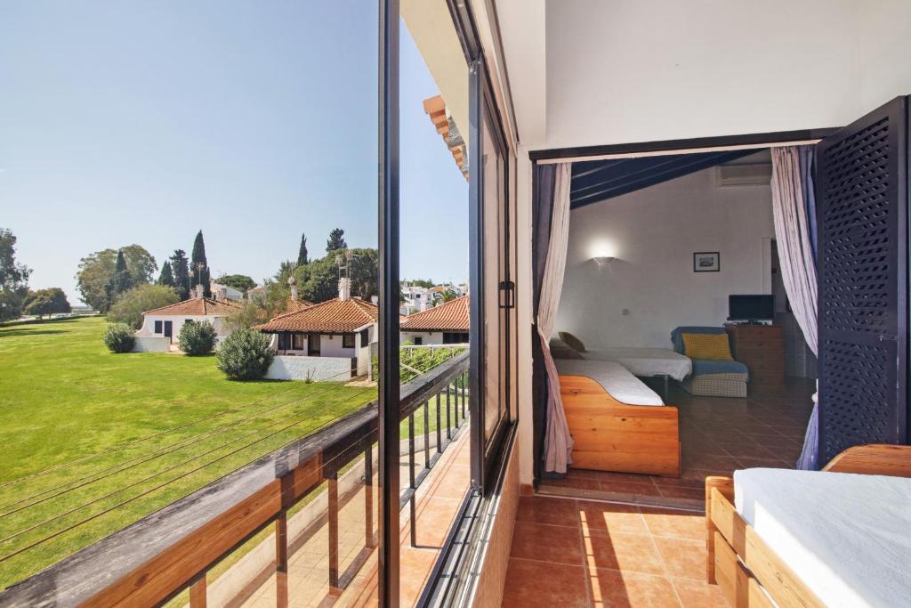 a bedroom with a balcony with a view of a yard at Pedras Del Rei 26 in São Pedro