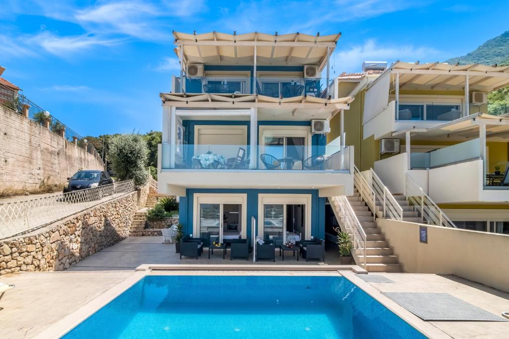 a villa with a swimming pool in front of a house at Oceanida Aelia room in Nikiana