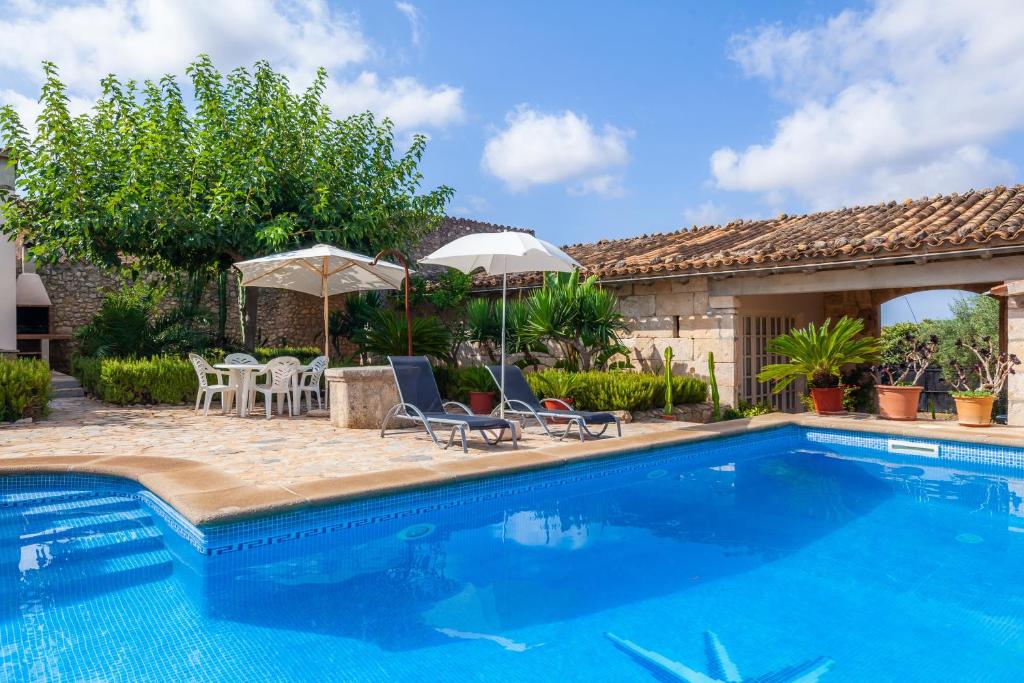 a swimming pool with chairs and umbrellas next to a house at S'alqueria Vell in Campanet
