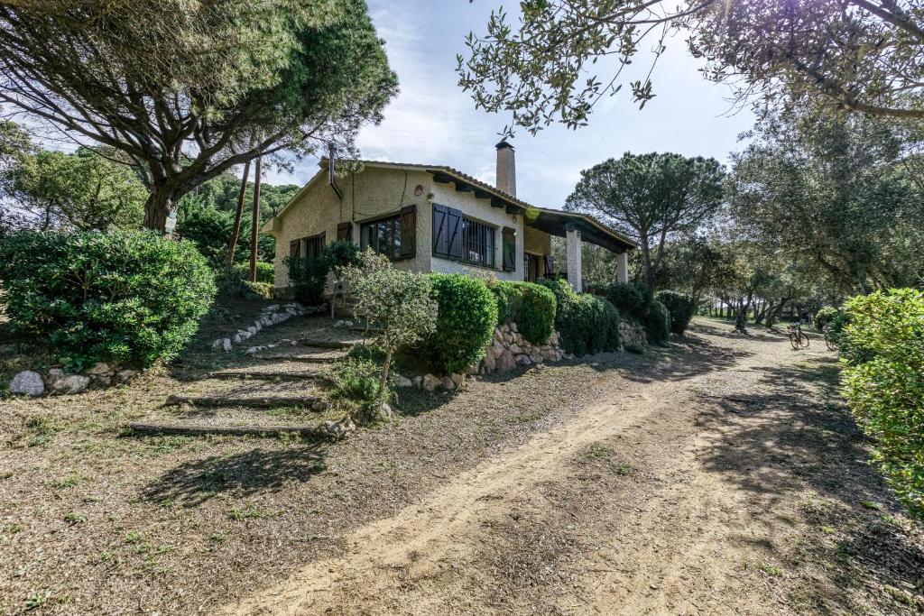 a house on a dirt road next to trees at La Barraca de Farena in Palafrugell