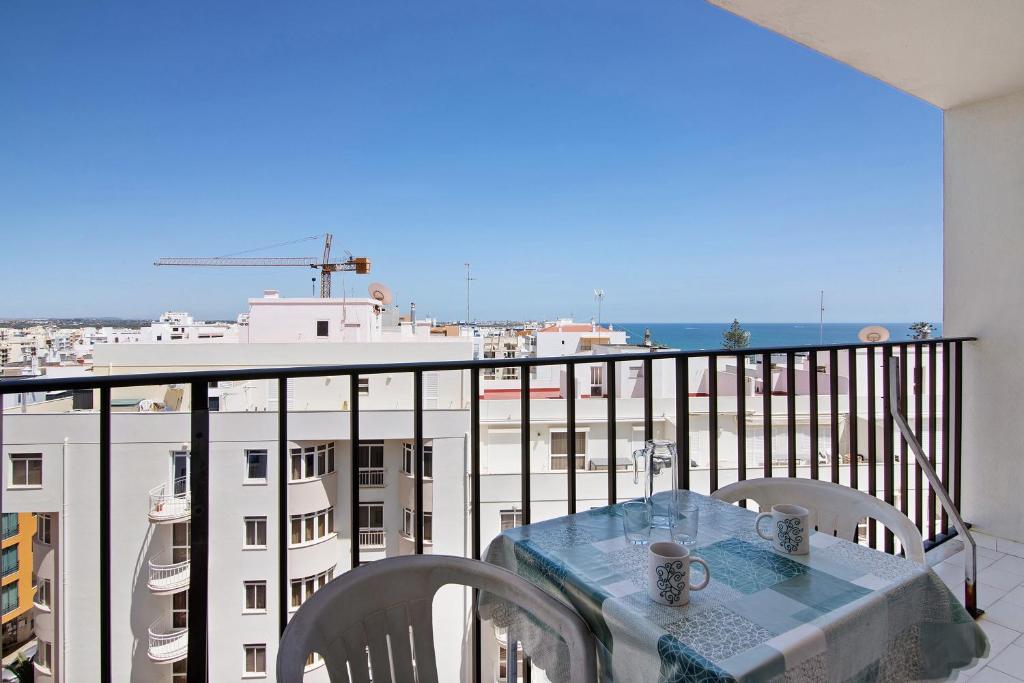 a table on a balcony with a view of a city at Casa Enxame in Armação de Pêra