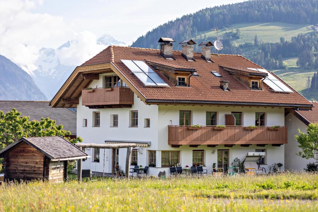 a house on a hill with mountains in the background at Oberhölzlhof in Valdaora di Sopra