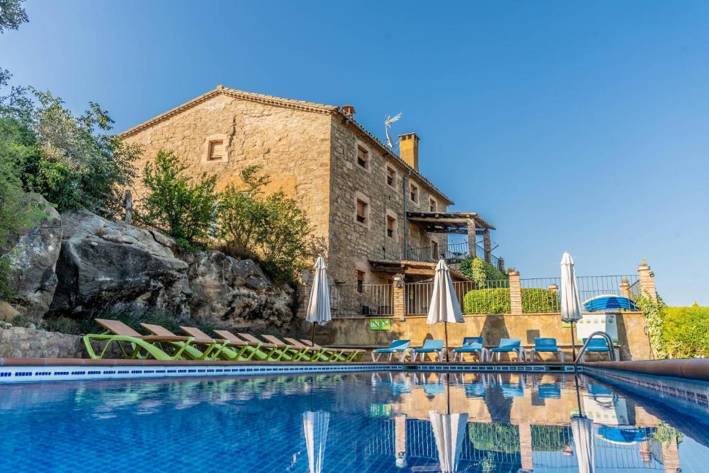 a swimming pool with chairs and umbrellas in front of a building at Sant Grau I in Navés