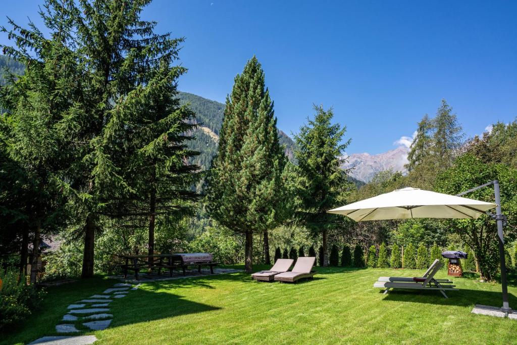 a patio with an umbrella and chairs on a lawn at Casa Ai Laresi 1 in Peio