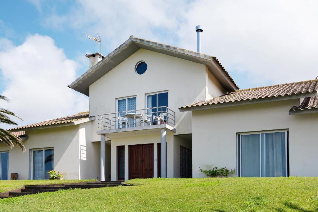 a white house with a balcony on top of it at Vivenda do Monte in Achadinha