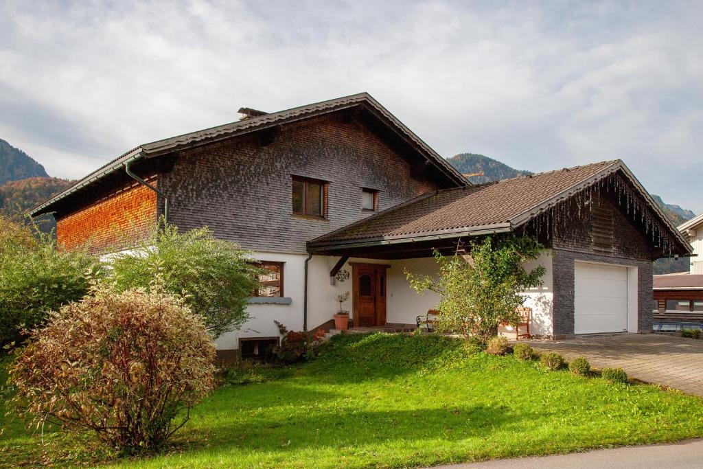 a house with a grassy yard with a garage at Ferienhaus Villa Kanisblick in Bizau
