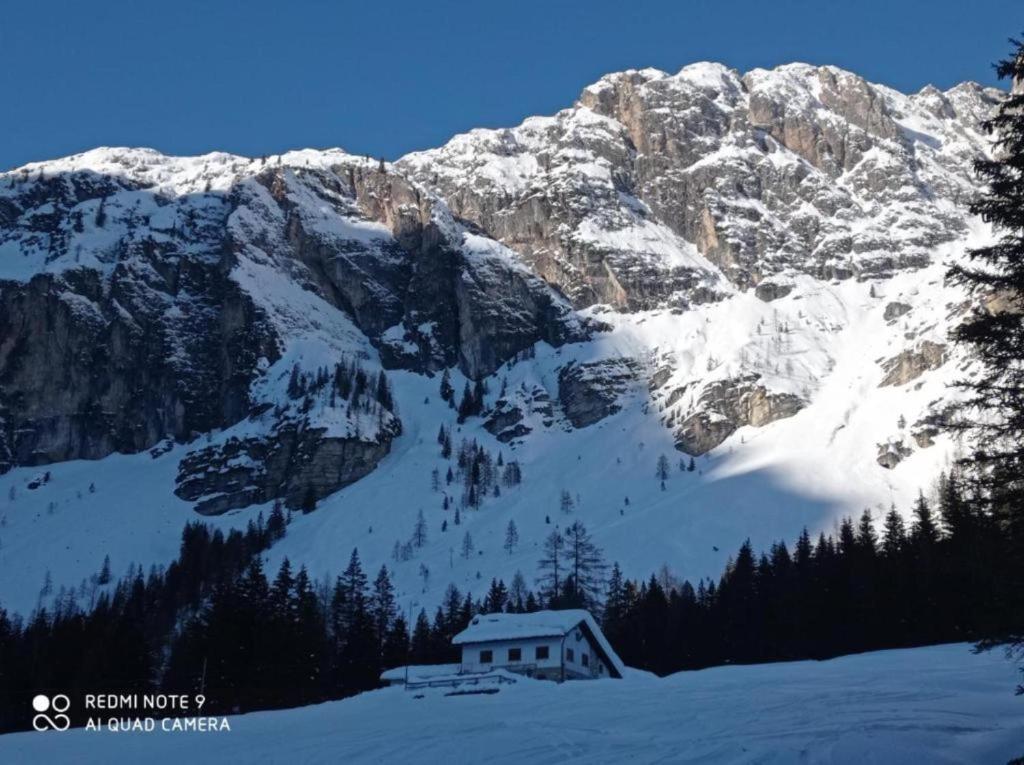 a snow covered mountain with a house in the foreground at Affittacamere da Annarè in Comèlico Superiore