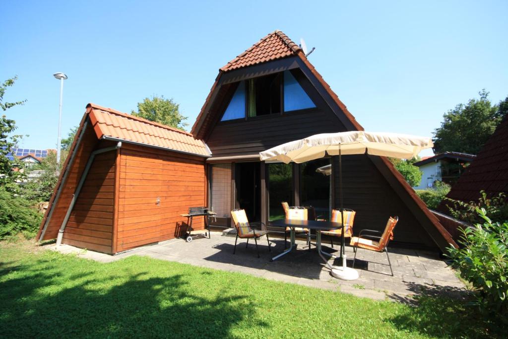 a house with an umbrella and a table and chairs at Gemütliches Nurdachhaus Bodensee in Immenstaad am Bodensee