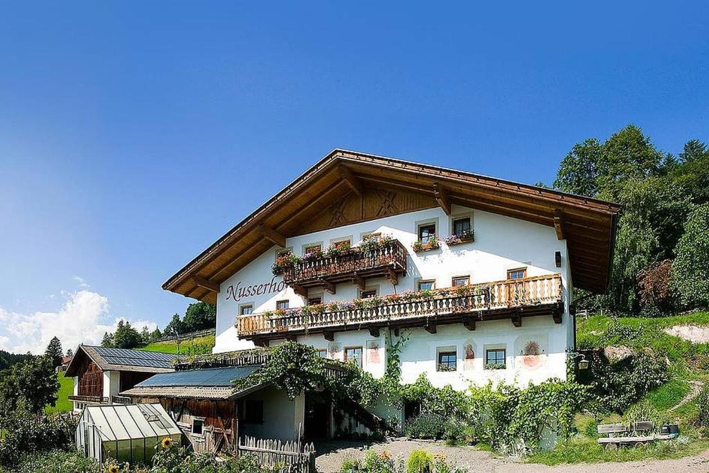 a large white building with a balcony on a hill at Ferienwohnung Aster Nusserhof in Avelengo