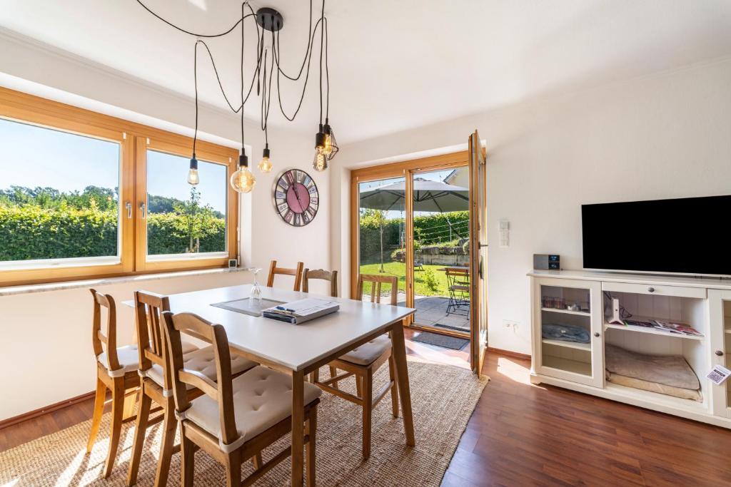a dining room with a table and chairs and a tv at Ferienwohnung Auszeit in Niederviehbach