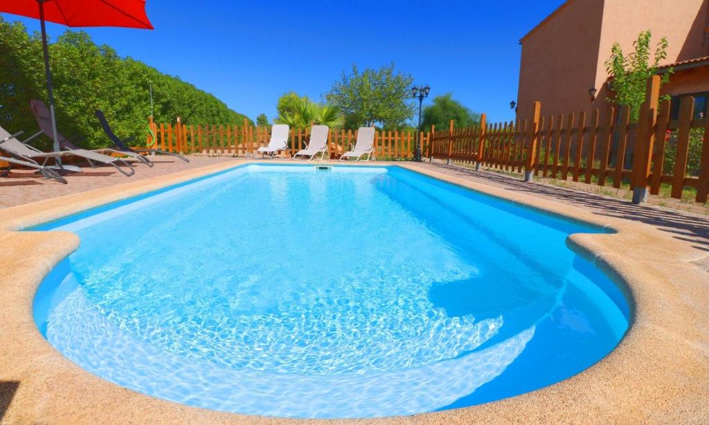 a swimming pool with chairs and an umbrella at Can Olivaret in Campos
