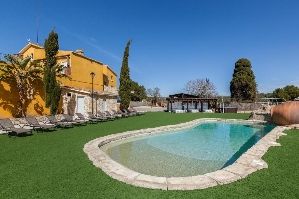 a swimming pool in a yard with chairs and a house at Masía Can Trabal in Olerdola