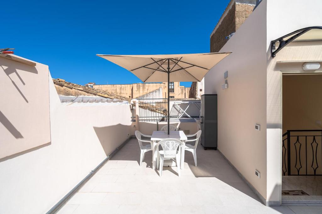 a balcony with a table and an umbrella at Il cappello sulle 23 in Avola