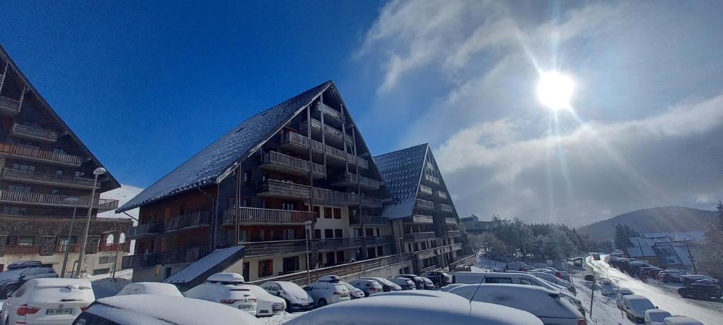 a snow covered building with cars parked in a parking lot at Appartement Le Maevan in Vassivière