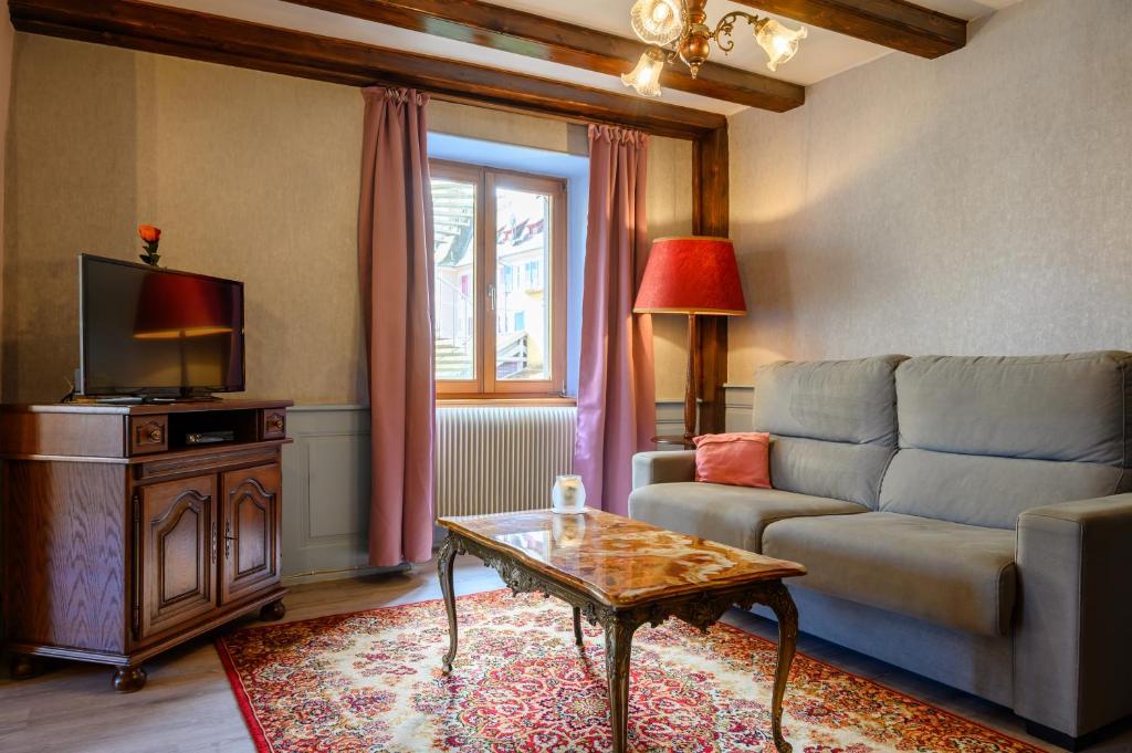 a living room with a couch and a tv at Gîte Le Rempart in Guebwiller