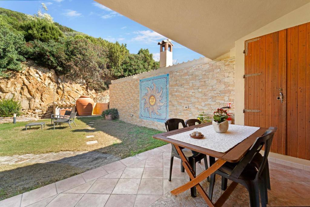 a patio with a table and chairs and a stone wall at Sole Mare di Barbara in Chia