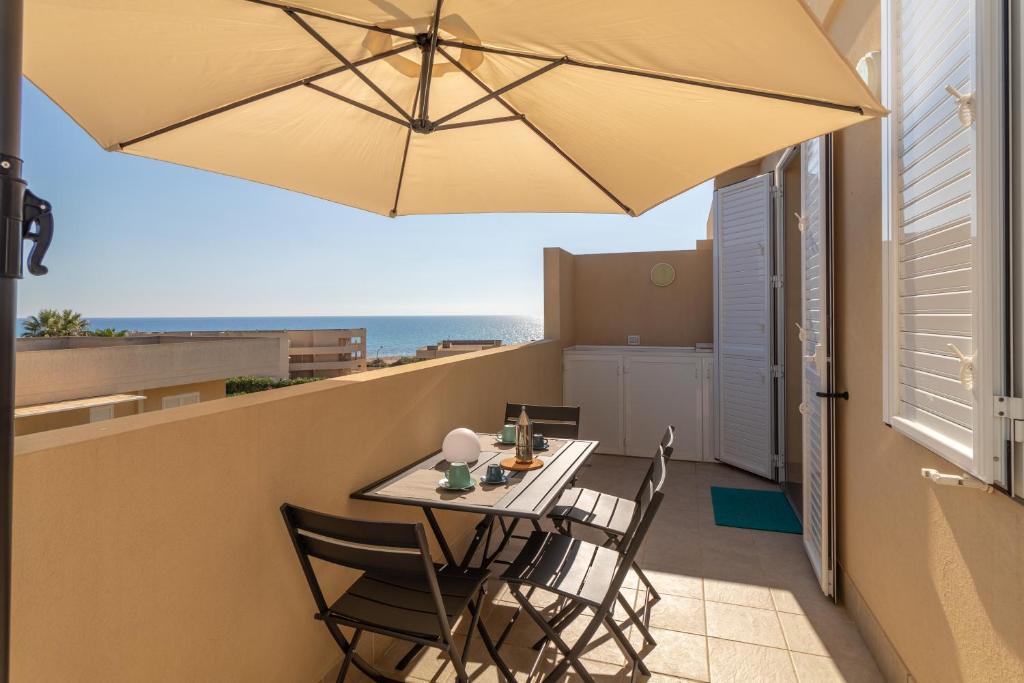 a table and chairs on a balcony with an umbrella at Brezzadisudest in Marina di Ragusa