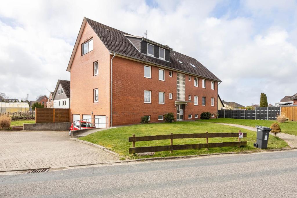 a large red brick house with a grassy yard at Ferienwohnung Krautsand in Drochtersen