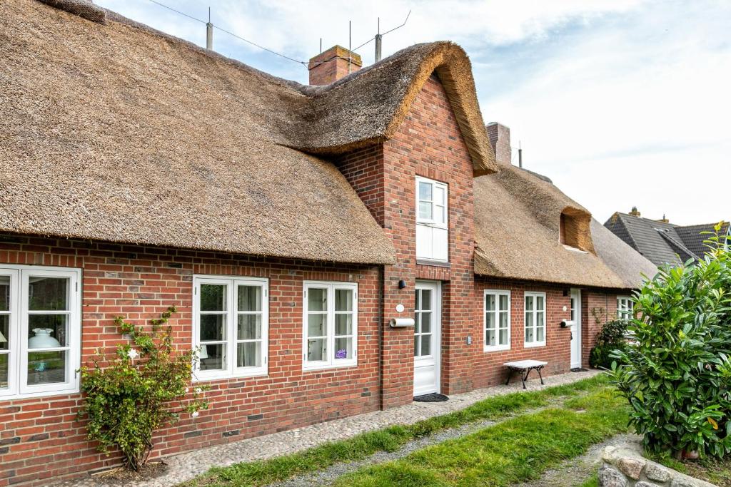 an old brick house with a thatched roof at Skriiwers Hüüs in Alkersum