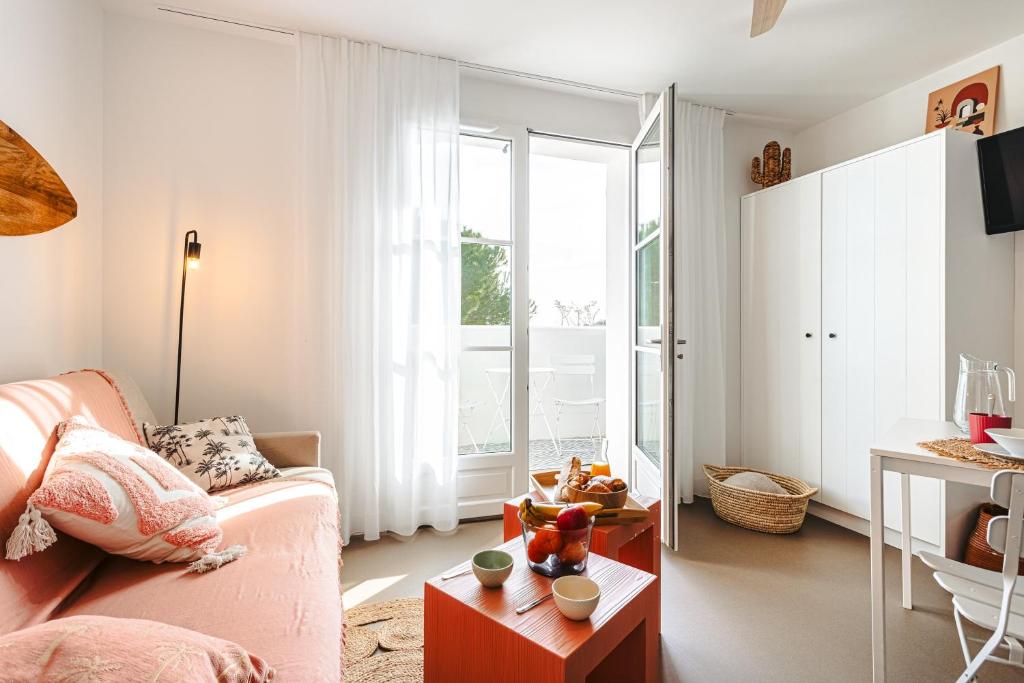 a living room with a pink couch and a table at Les Pins, Rivedoux Beach House in Rivedoux-Plage