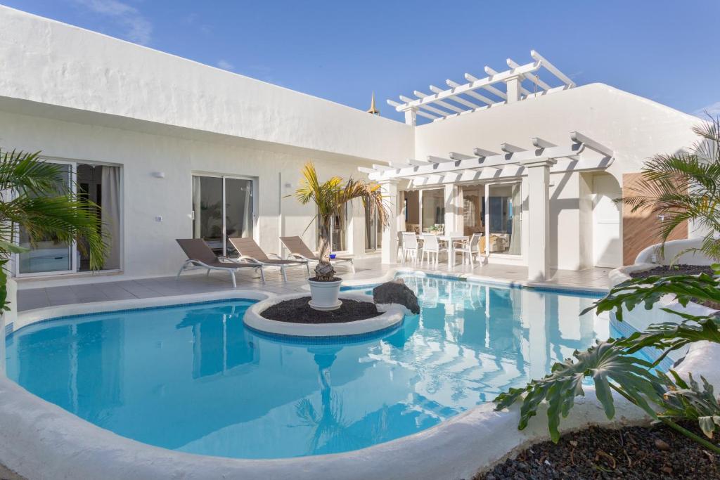 a swimming pool in front of a house at Villa Ole Bahiazul-Private Jacuzzi in Corralejo