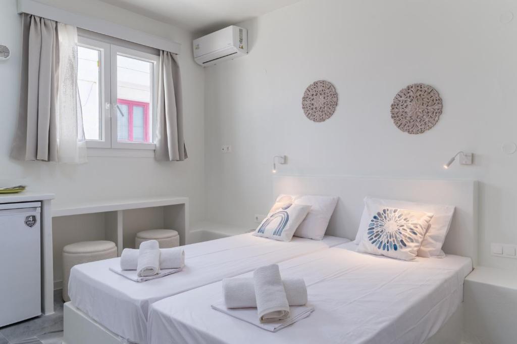 a white bedroom with a large bed with white sheets at A Tinian Room 1 in Tinos