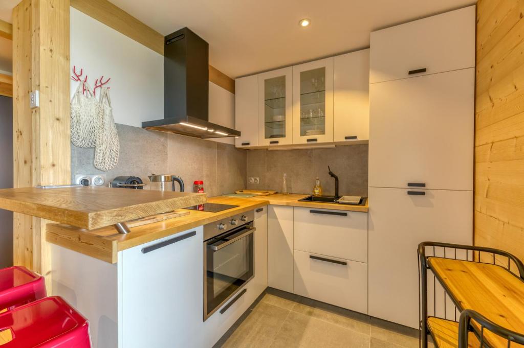a kitchen with white cabinets and a wooden table at Appartement Alpe d'huez in LʼHuez