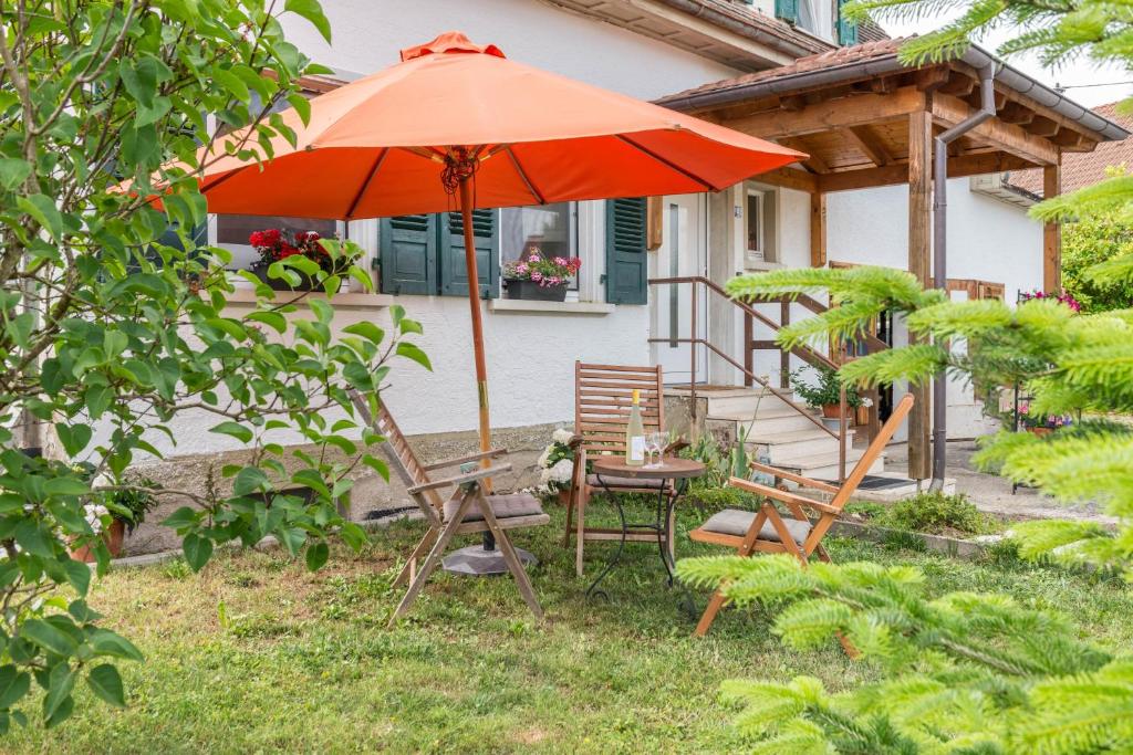 an orange umbrella and a table and chairs in a yard at Landhausloft in Bermatingen