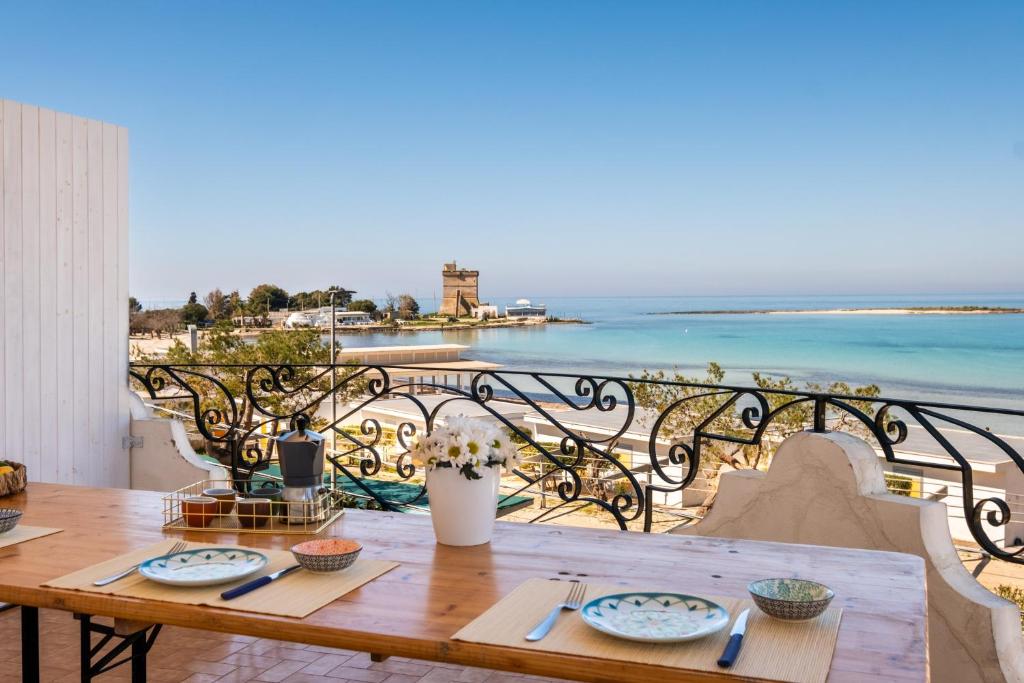 a table on a balcony with a view of the ocean at Villa Gaudì - Sagrada in Sant'Isidoro