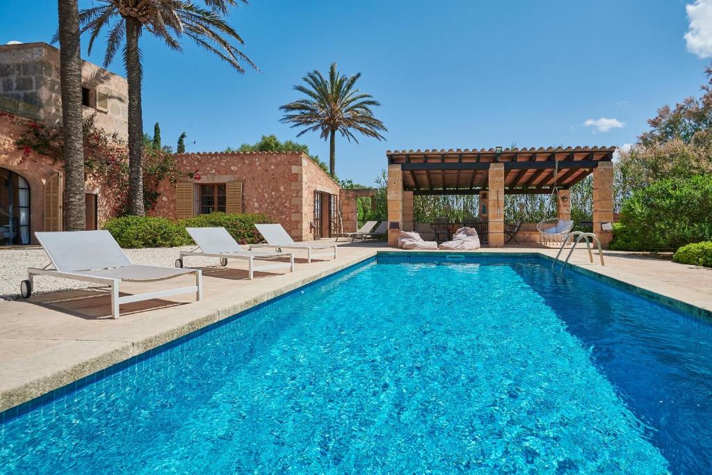 a swimming pool with chairs and a gazebo at Son Garreta in El Palmer