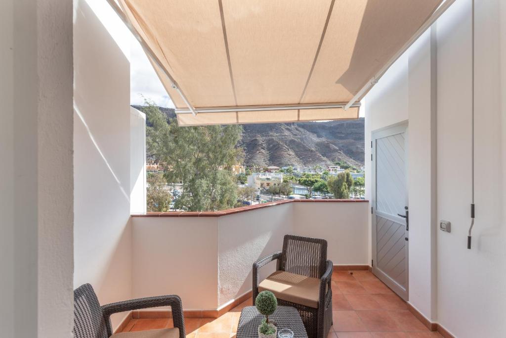 a balcony with chairs and a table with a view at Vv Faro in Puerto de Mogán