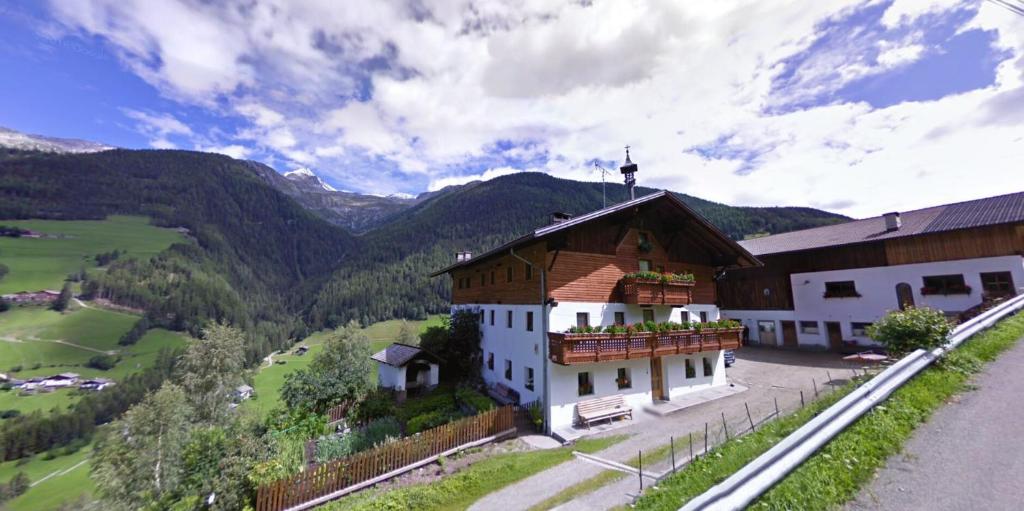 a building on a hill with mountains in the background at Oberhöher Apt Talblick in San Pietro