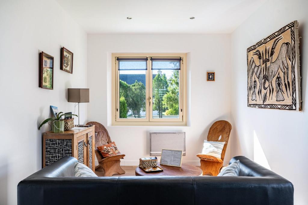 a living room with a black leather couch at Gîte Ty Berniques in Pléneuf-Val-André