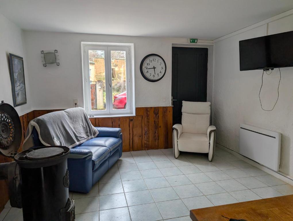 a living room with a couch and a clock on the wall at Gîte chez mémé in Assieu